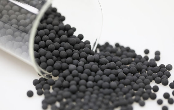 Black activated carbon ceramic balls spilling from a glass beaker (media maker's photo)