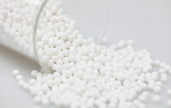 White calcium sulfite ceramic balls spilling from a glass beaker (media maker's photo)