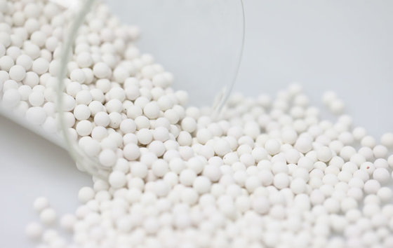 White silver-containing ceramic balls spilling from a glass beaker (media maker's photo)