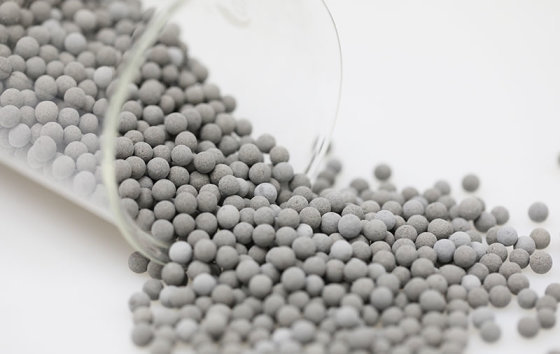 Grey tourmaline ceramic balls spilling from a glass beaker (media maker's photo)